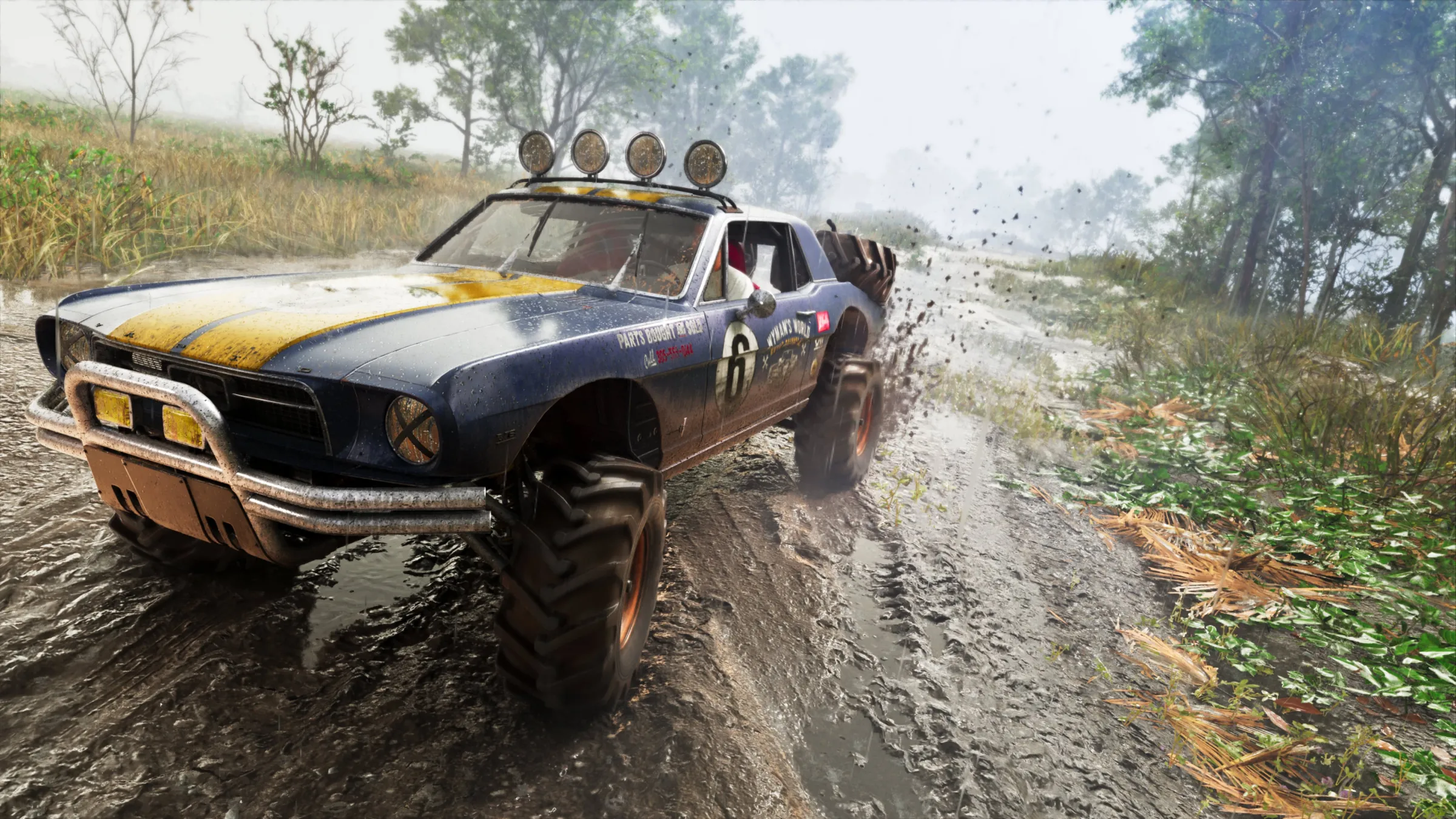 A lifted black and yellow off-road car throws mud as it races along a wet woodland track.